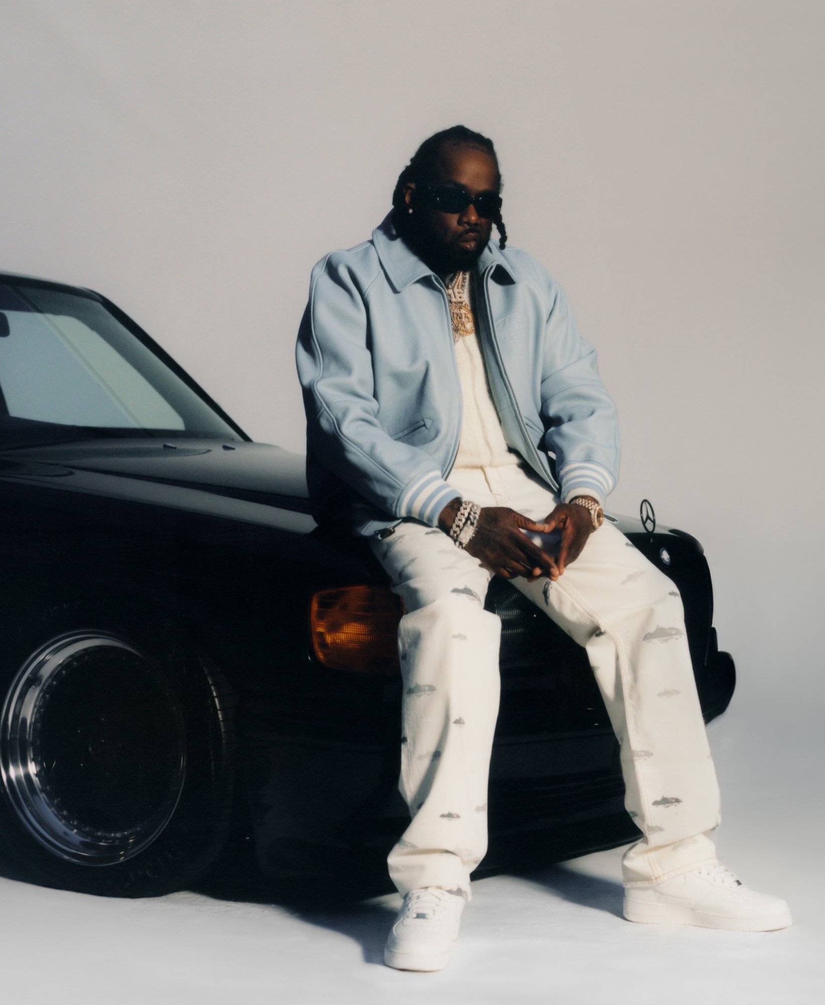 Conway The Machine seated on the bonnet of a black Mercedes against a seamless studio backdrop — final retouched frame