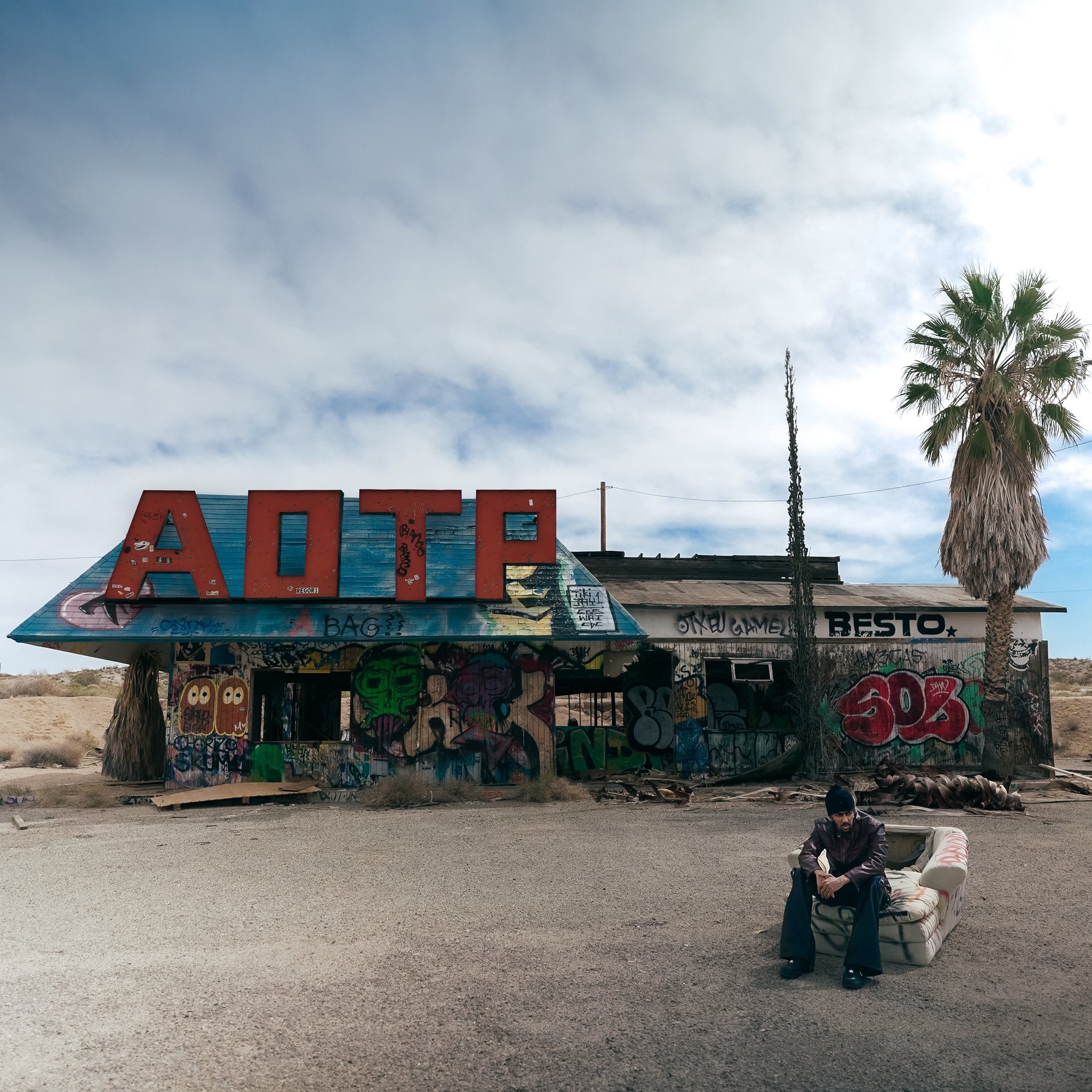 AOTP — final front cover, abandoned desert diner with AOTP sign letters and figure on a sofa